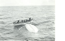 Photograph of five men in a lifeboat from the Mackay-Bennet examining an overturned lifeboat from...