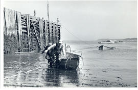 Photograph of two men pulling a salvaged boat ashore at Seal Island, off Cape Sable Island