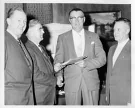 Photograph of four men side by side, two shaking hands