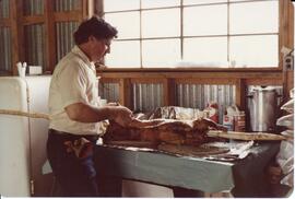 Photograph of a person who is likely preparing a lamb or sheep carcass for roasting during the fi...