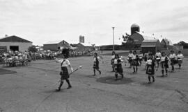 Photographic negative of pipe and drum band marching in a parking lot at the Nova Scotia Agricult...