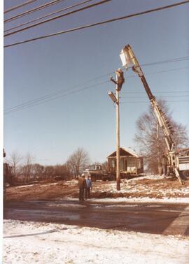 Photograph of the moving of power or telephone lines so that a house can be moved off of the NSAC...
