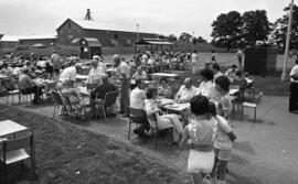 Photographic negative of people sitting at tables outdoors at the Nova Scotia Agricultural Colleg...