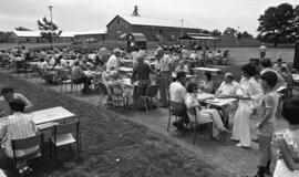 Photographic negative of people sitting at tables outdoors at the Nova Scotia Agricultural Colleg...